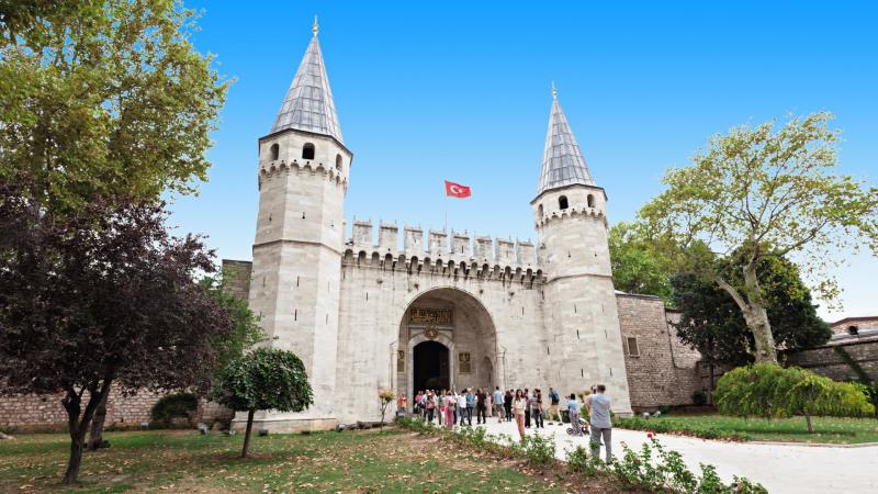 Stone entrance to Topkapi palace featuring two towers 