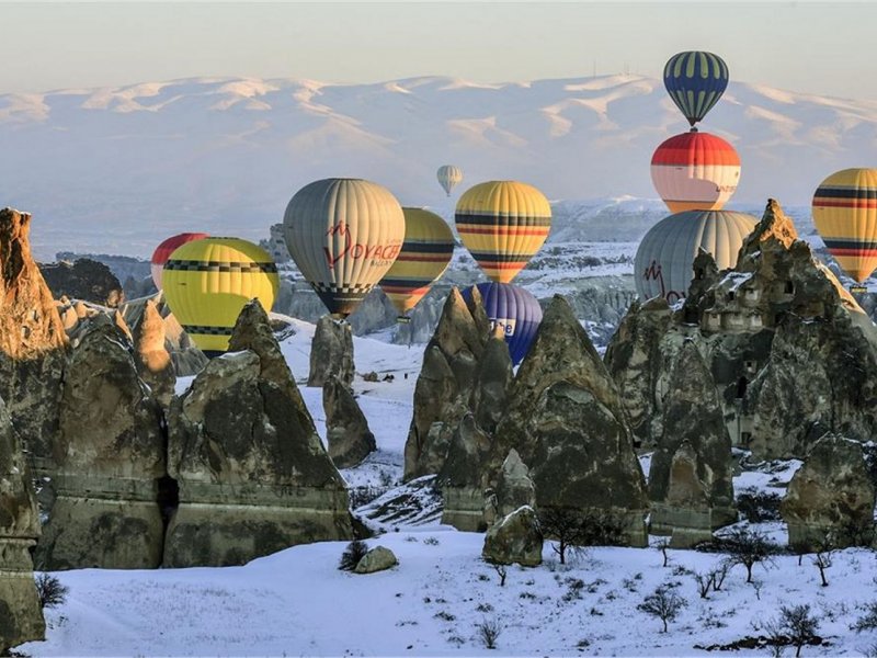 Hot air balloons floating across a snow-covered landscape