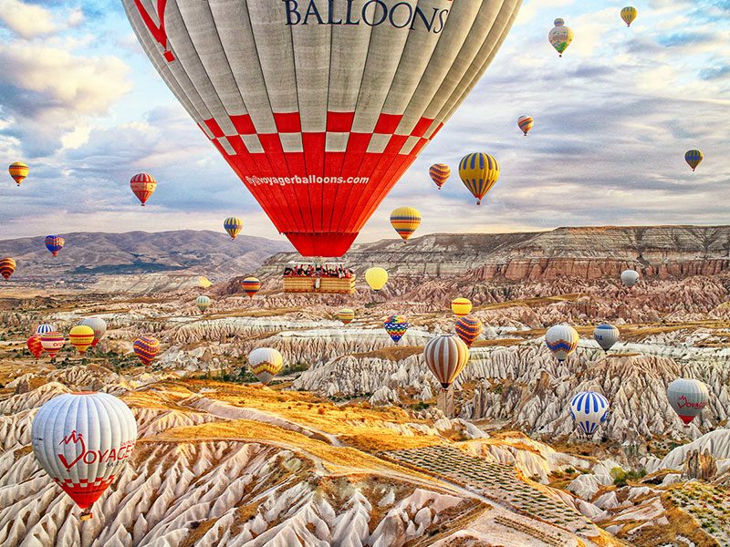 Hot air balloons floating across rock formations and valleys