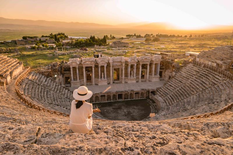 Young woman overlooking blue travertines of Hierapolis ancient city