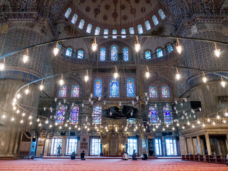 Image of large chandelier, tiles and stained-glass windows in Blue Mosque