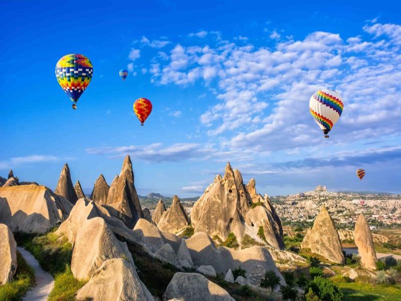 Hot air balloons floating above fairy chimneys on sunny day