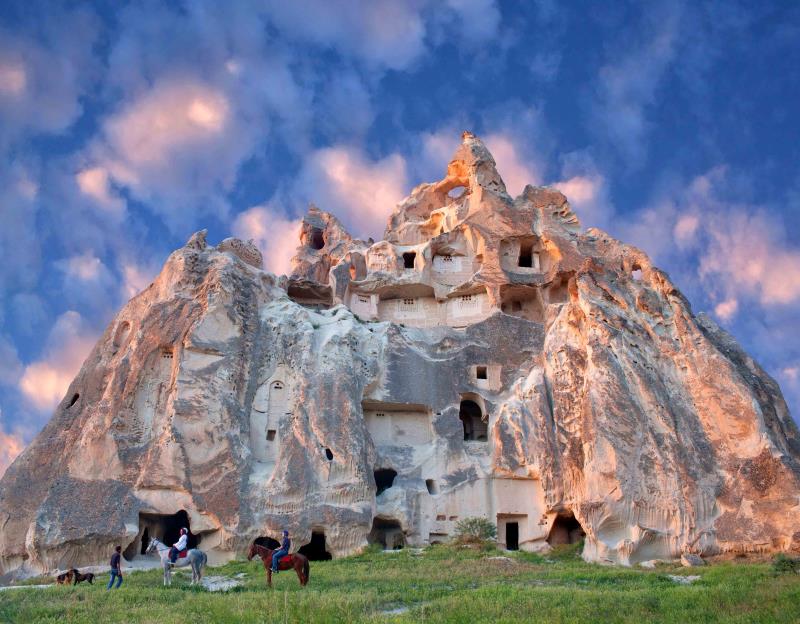 People on horseback in front of rock formations in Cappadocia