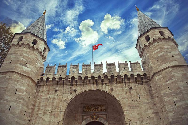 Stone entrance to Topkapi palace featuring two towers 