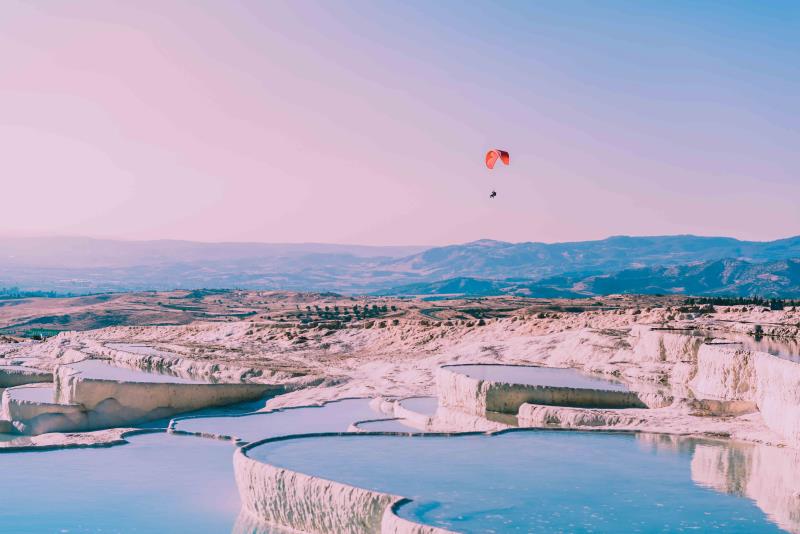 Image of Pamukkale’s Blue travertine terraces and person skydiving